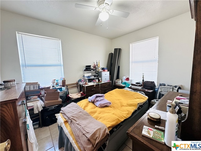 tiled bedroom with ceiling fan and a textured ceiling