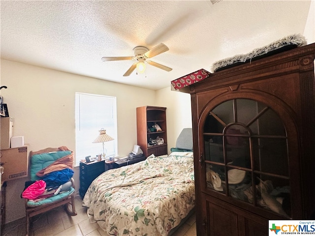 tiled bedroom with a textured ceiling and ceiling fan