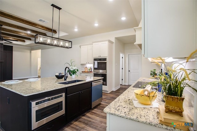 1010 Winchester Dr, Nolanville, TX 76559 - kitchen featuring appliances with stainless steel finishes, white cabinets, dark wood-style floors, light stone counters, and a kitchen island with sink