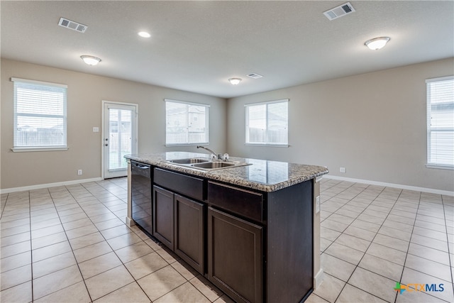 kitchen featuring light tile patterned flooring, a center island with sink, sink, and dishwasher