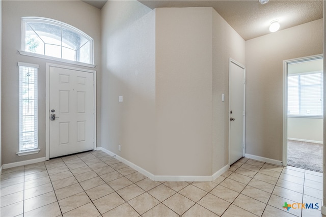 foyer with a textured ceiling and light tile patterned floors