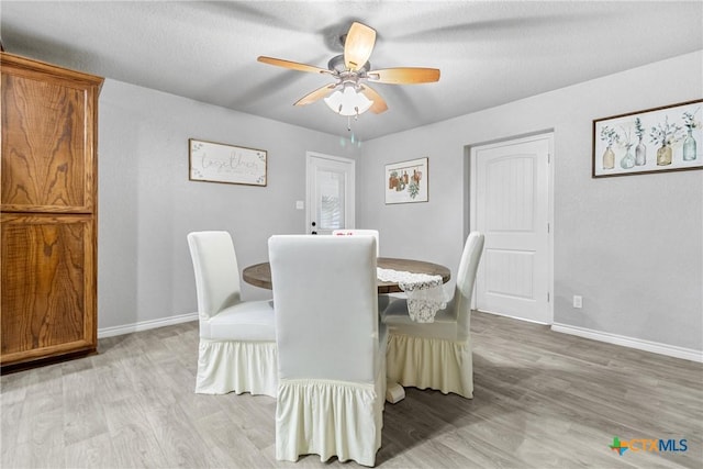 dining room featuring light wood finished floors, baseboards, and a ceiling fan
