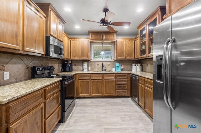 kitchen featuring stainless steel appliances, a ceiling fan, a sink, and brown cabinets
