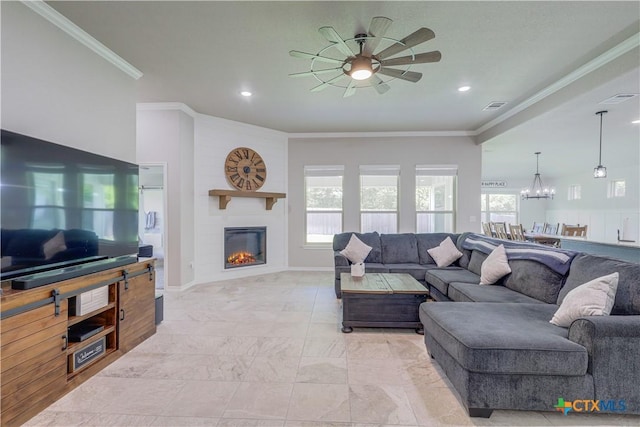 living room with crown molding, a large fireplace, and ceiling fan with notable chandelier