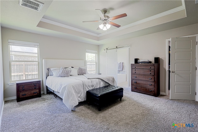 carpeted bedroom featuring a raised ceiling, connected bathroom, ceiling fan, and crown molding