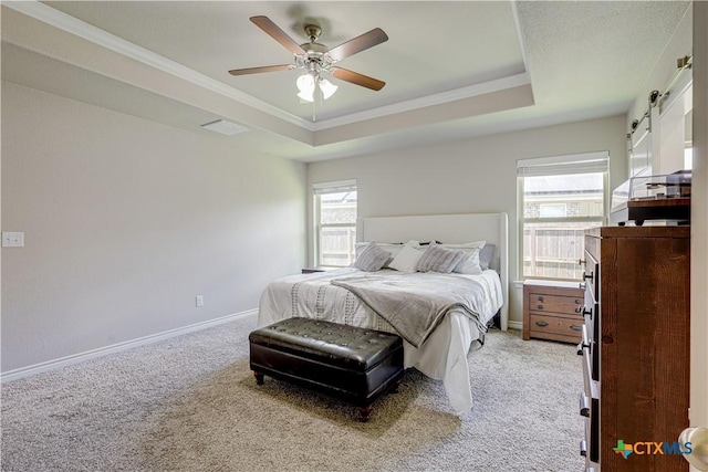 carpeted bedroom with ceiling fan, a raised ceiling, and ornamental molding