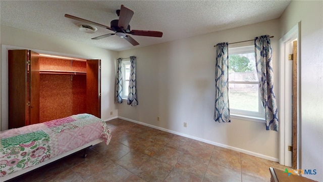 bedroom featuring ceiling fan, a textured ceiling, a closet, and tile patterned floors