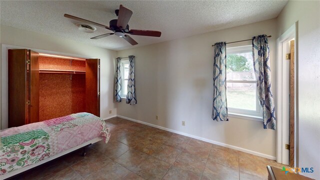 bedroom featuring ceiling fan, a textured ceiling, a closet, and tile patterned floors