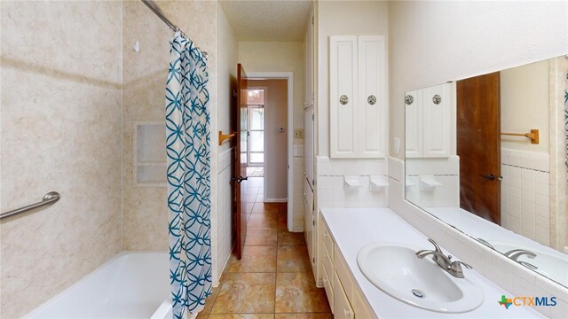 bathroom featuring tile patterned flooring, shower / tub combo, a textured ceiling, vanity, and tile walls