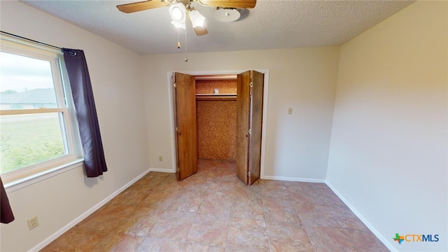 unfurnished bedroom featuring ceiling fan, a textured ceiling, and a closet