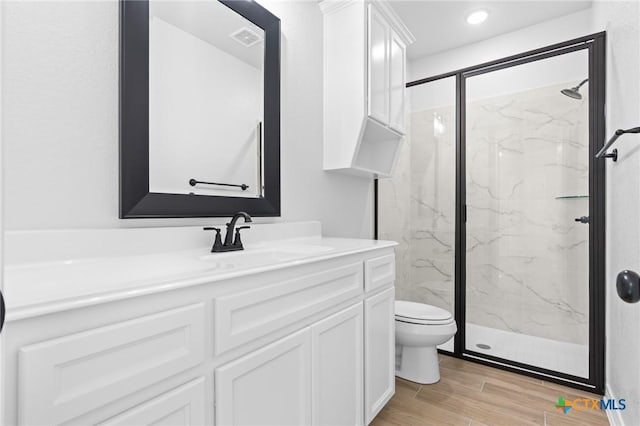 bathroom featuring vanity, hardwood / wood-style flooring, toilet, and walk in shower