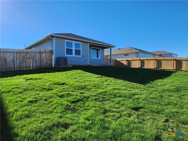 rear view of property featuring cooling unit and a yard