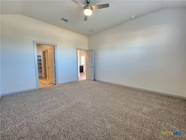 unfurnished bedroom featuring light carpet, a walk in closet, vaulted ceiling, and ceiling fan