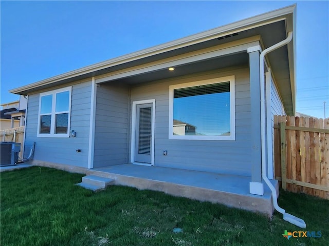 rear view of house with central AC, a yard, and a patio