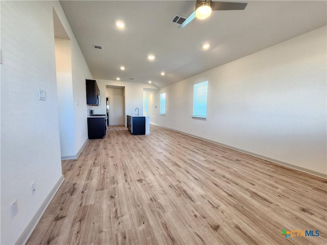 unfurnished living room with ceiling fan, sink, and light wood-type flooring