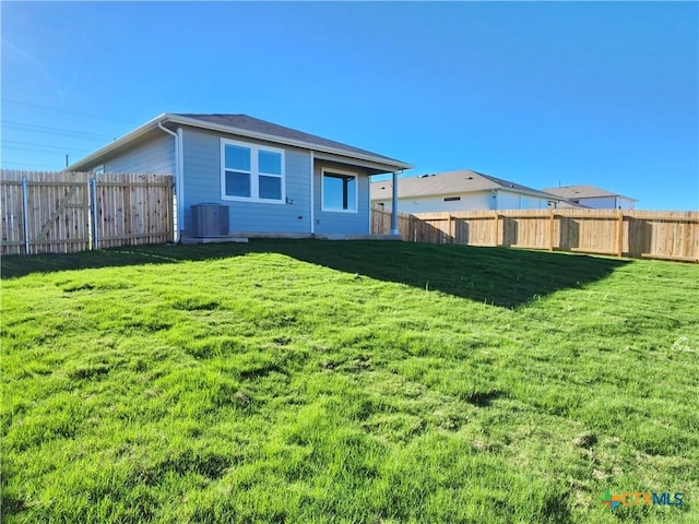 rear view of house featuring central AC unit and a lawn