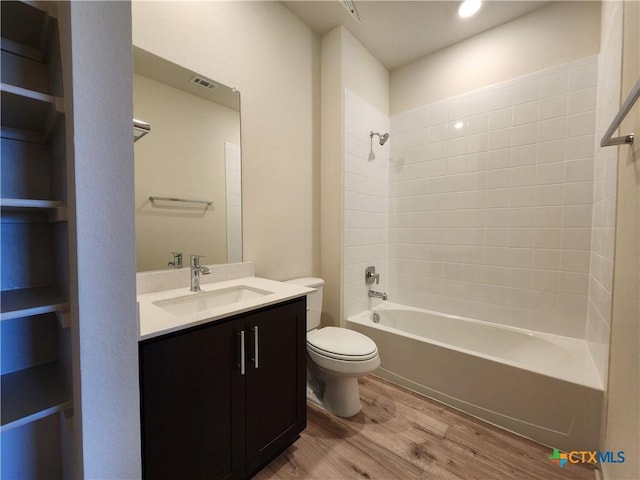 full bathroom with tiled shower / bath, wood-type flooring, vanity, and toilet