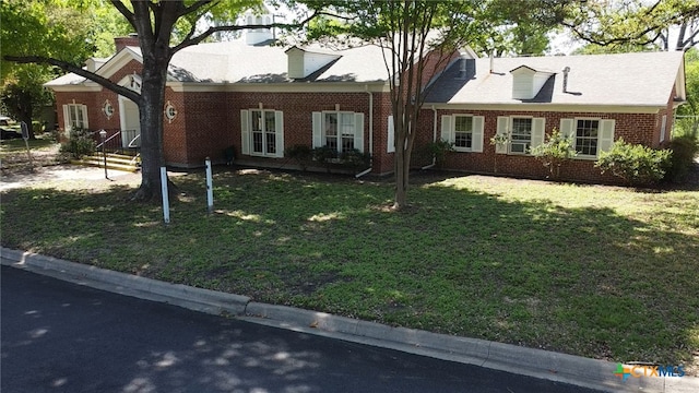 cape cod house with a front lawn and brick siding