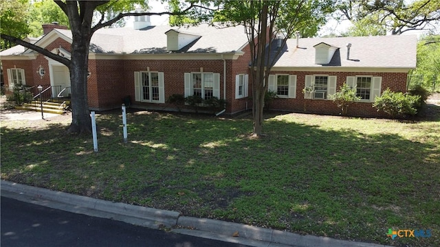 cape cod home with brick siding and a front lawn