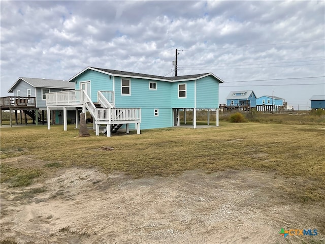 back of house with a deck and a lawn