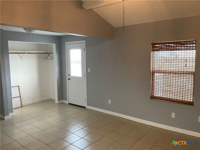 unfurnished bedroom featuring light tile patterned floors, a closet, and vaulted ceiling