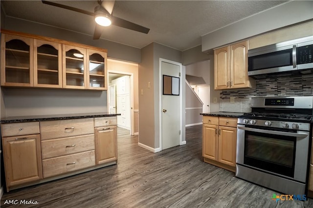 kitchen with dark hardwood / wood-style floors, tasteful backsplash, dark stone countertops, stainless steel appliances, and light brown cabinets