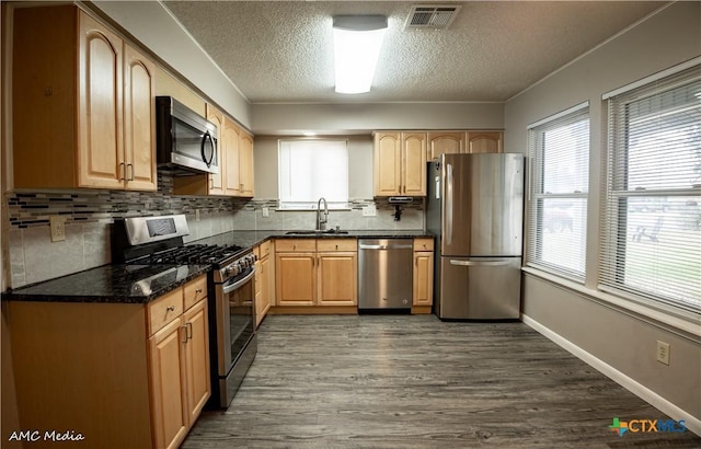 kitchen featuring appliances with stainless steel finishes, tasteful backsplash, sink, dark hardwood / wood-style flooring, and a textured ceiling