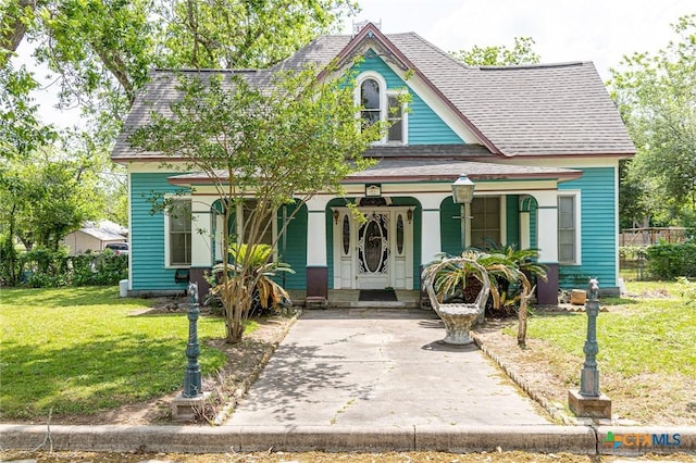 204 Ave F, Shiner, TX 77984 - victorian home with covered porch, roof with shingles, and a front lawn