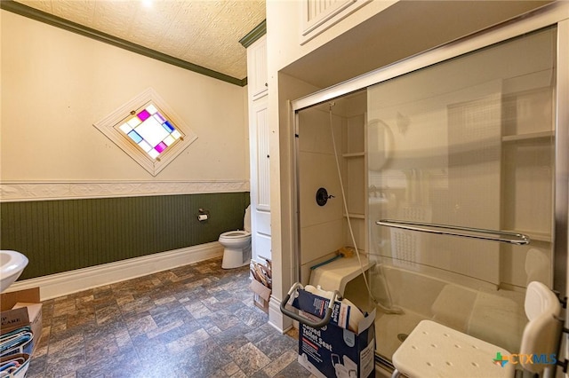 204 Ave F, Shiner, TX 77984 - bathroom with a shower with shower door, ornamental molding, toilet, and a wainscoted wall