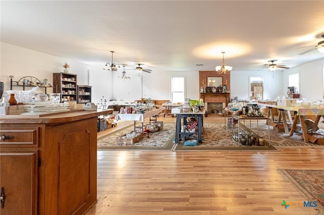 204 Ave F, Shiner, TX 77984 - kitchen with brown cabinets, light wood-style flooring, ceiling fan with notable chandelier, open floor plan, and decorative light fixtures