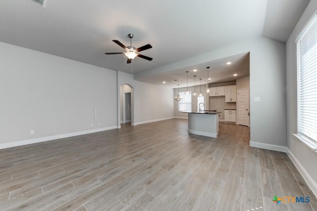 unfurnished living room featuring light hardwood / wood-style floors, a wealth of natural light, and ceiling fan