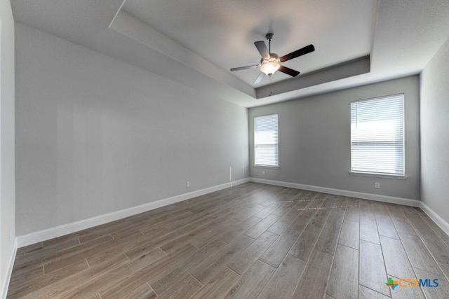 unfurnished room with a tray ceiling, ceiling fan, and hardwood / wood-style floors