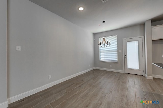 unfurnished dining area with light hardwood / wood-style floors and a chandelier