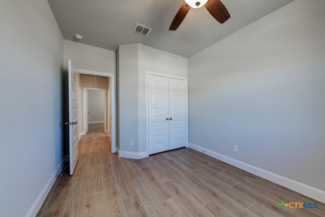 unfurnished bedroom featuring ceiling fan, light hardwood / wood-style floors, and a closet