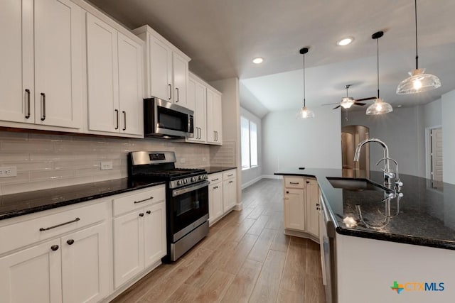 kitchen with a kitchen island with sink, sink, appliances with stainless steel finishes, decorative light fixtures, and white cabinetry