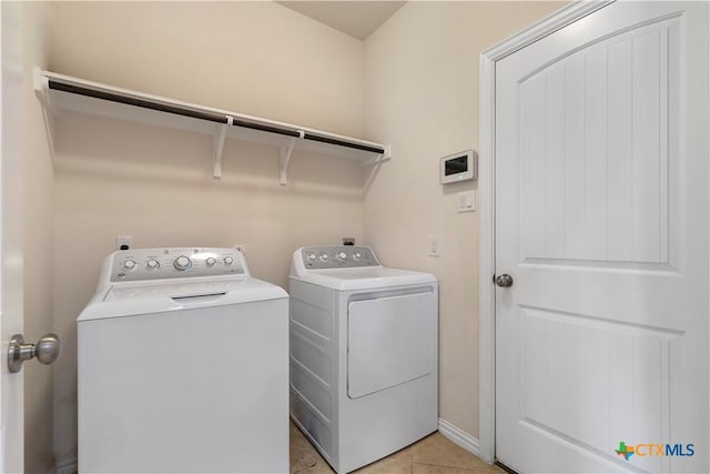 laundry area with washing machine and clothes dryer and light tile patterned floors