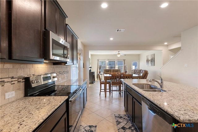 kitchen featuring light stone counters, sink, backsplash, and appliances with stainless steel finishes