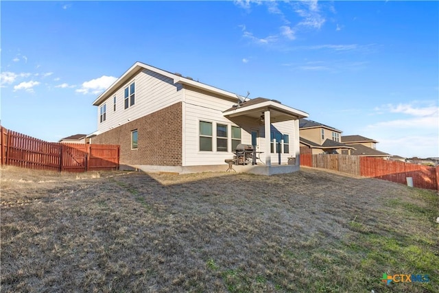 rear view of property featuring a lawn and a patio area