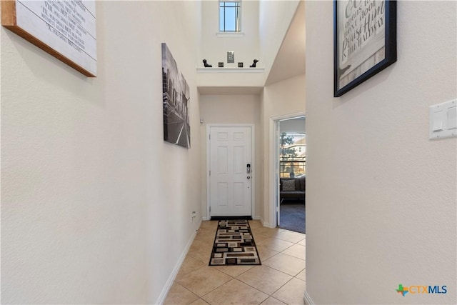 entryway with light tile patterned flooring and a high ceiling