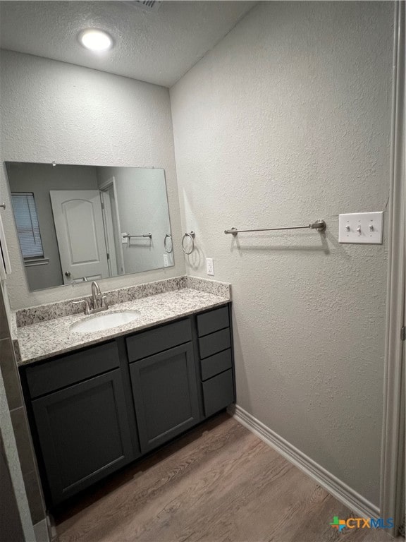 bathroom with hardwood / wood-style floors, vanity, and a textured ceiling