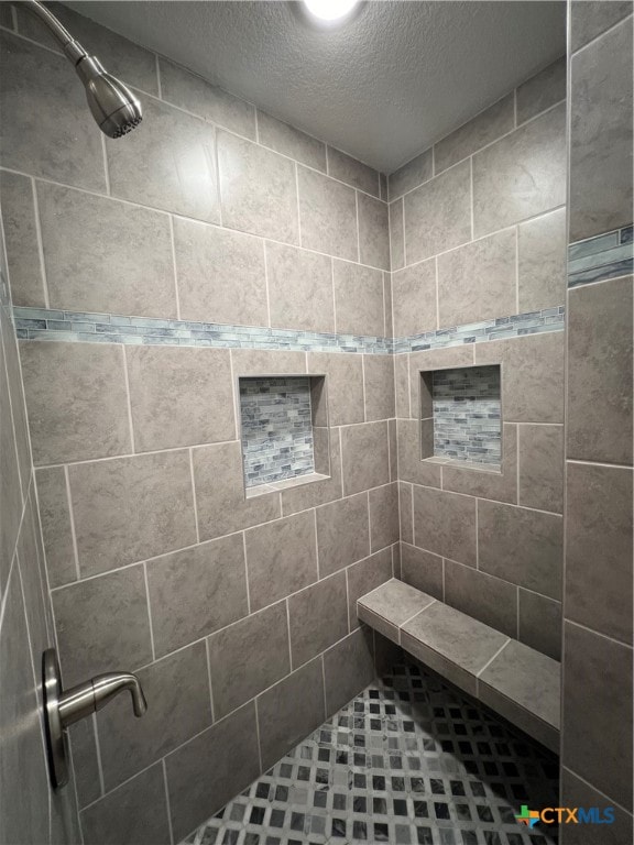 bathroom with tiled shower and a textured ceiling