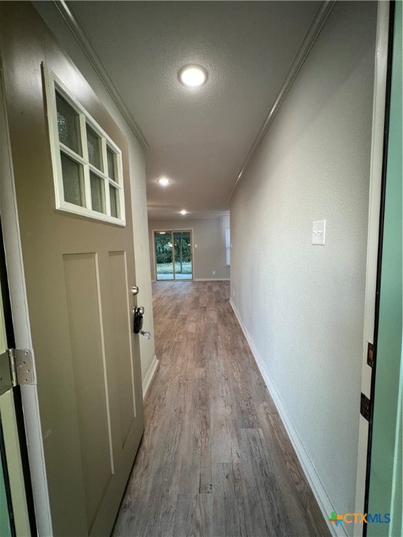 corridor with crown molding, a textured ceiling, and hardwood / wood-style flooring