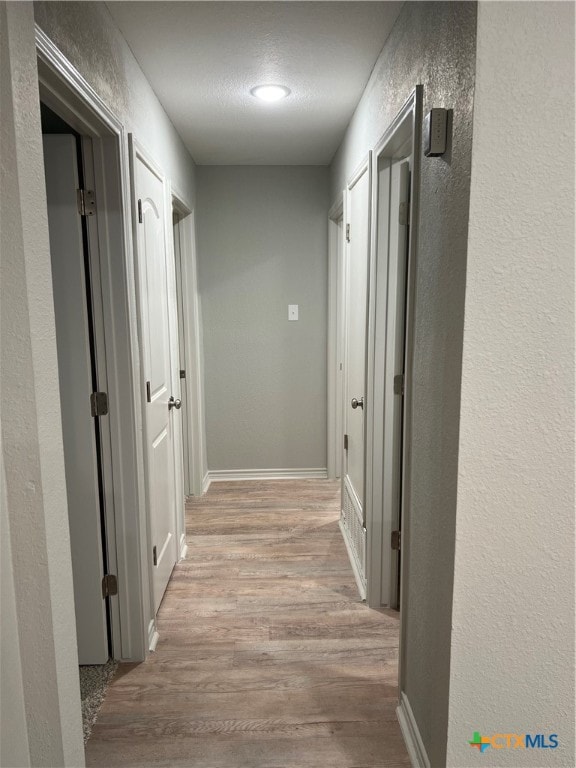 hall featuring a textured ceiling and light hardwood / wood-style flooring