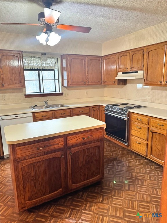 kitchen with ceiling fan, a center island, sink, white dishwasher, and range