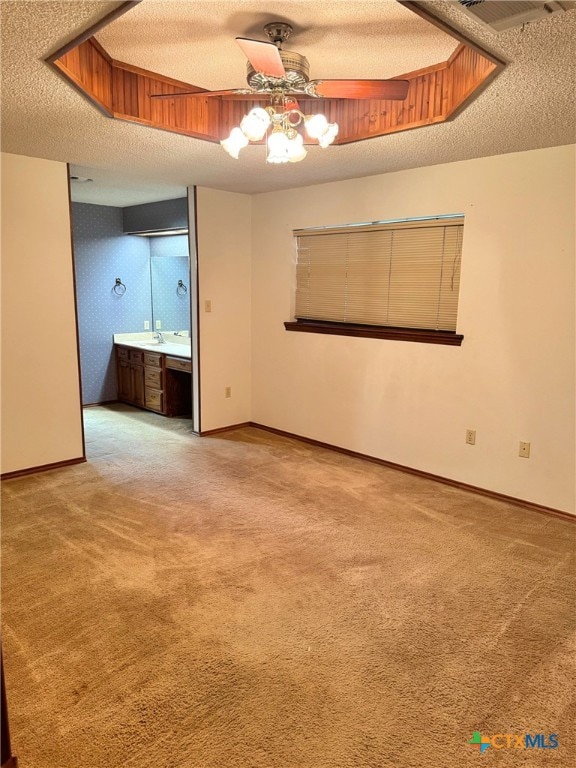 spare room with ceiling fan, carpet floors, a textured ceiling, and a tray ceiling