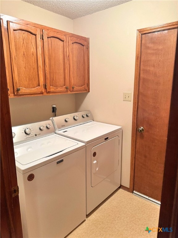 washroom featuring cabinets, a textured ceiling, and separate washer and dryer