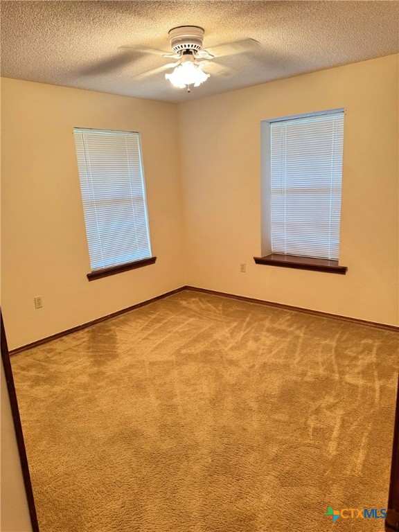 carpeted spare room featuring a textured ceiling and ceiling fan