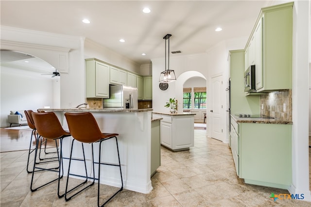 112 Oak Plaza Dr, Georgetown, TX 78628 - kitchen with stainless steel appliances, a ceiling fan, a peninsula, arched walkways, and ornamental molding
