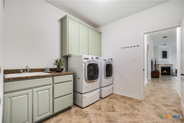 112 Oak Plaza Dr, Georgetown, TX 78628 - laundry area with washing machine and clothes dryer, cabinet space, a lit fireplace, baseboards, and light stone finish floors
