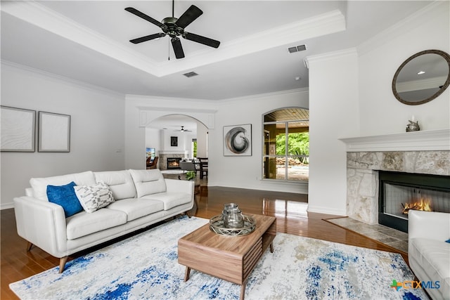112 Oak Plaza Dr, Georgetown, TX 78628 - living area with a raised ceiling, arched walkways, a fireplace with flush hearth, wood finished floors, and crown molding